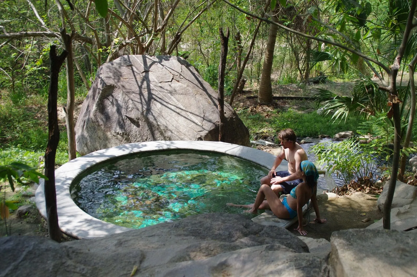 Couple relaxing at natural hot springs pool surrounded by jungle