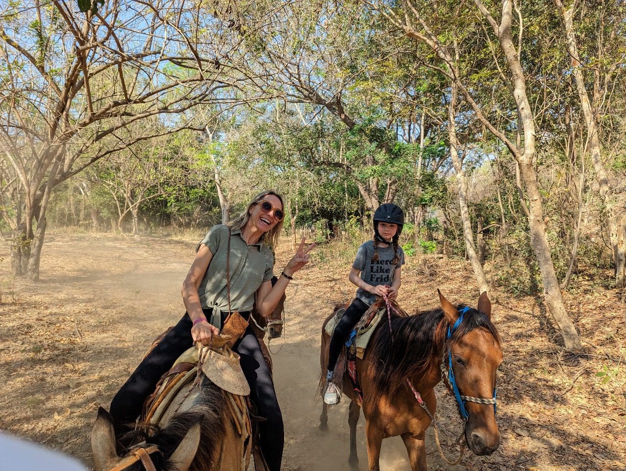 Mother and child enjoying horseback ride through jungle