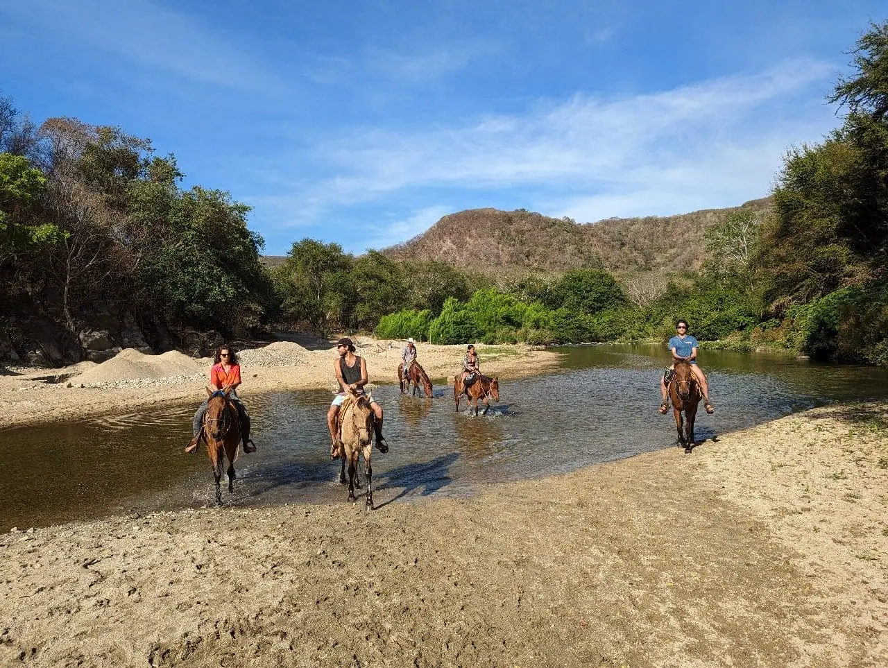 Horseback riders crossing river in scenic valley