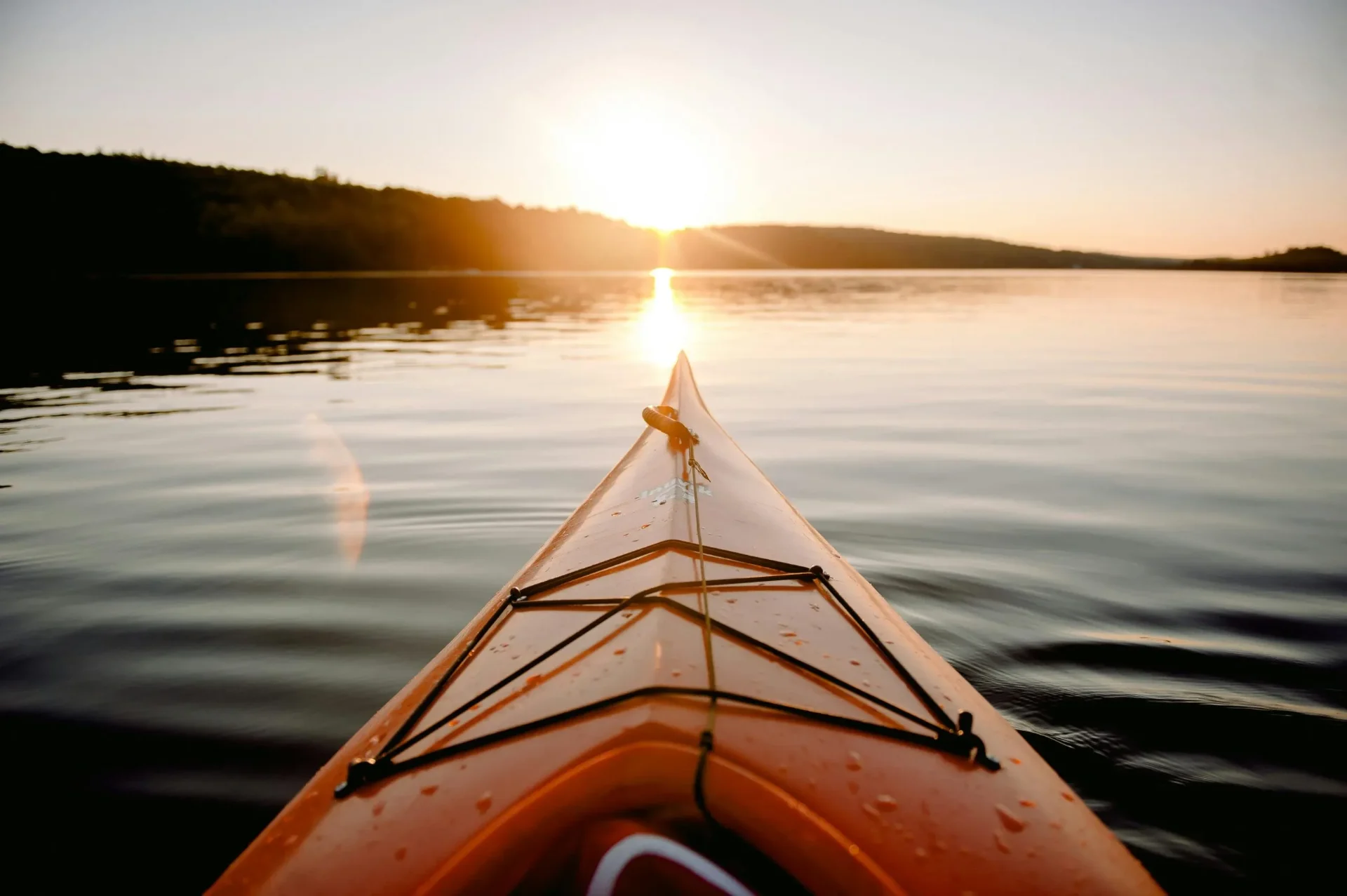 Kayak bow pointed toward sunset on calm water